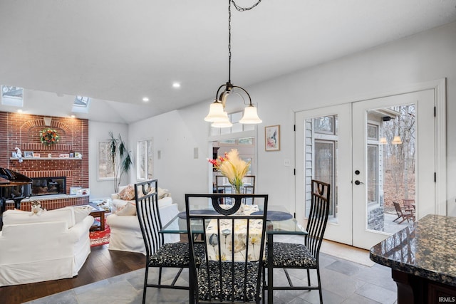 dining room with vaulted ceiling, french doors, a brick fireplace, and recessed lighting