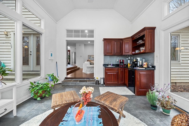 bar featuring high vaulted ceiling, stone finish flooring, a sink, and tasteful backsplash