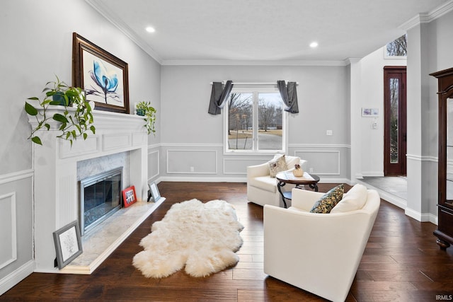 living area with ornamental molding, a high end fireplace, a decorative wall, and wood finished floors