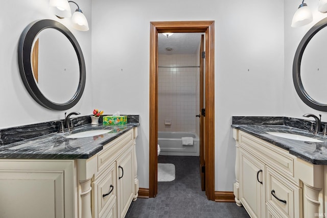 full bathroom with two vanities, a sink, and baseboards