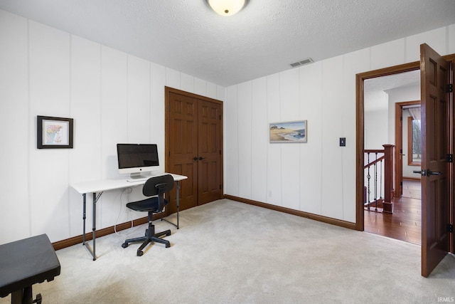 office featuring a textured ceiling, visible vents, and carpet flooring