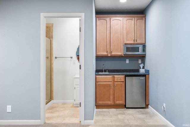 kitchen with refrigerator, stainless steel microwave, a sink, and baseboards