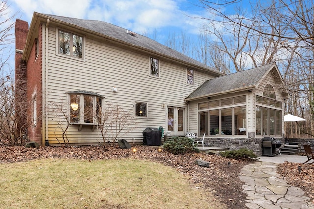 rear view of property with a lawn, a patio, a sunroom, a chimney, and french doors