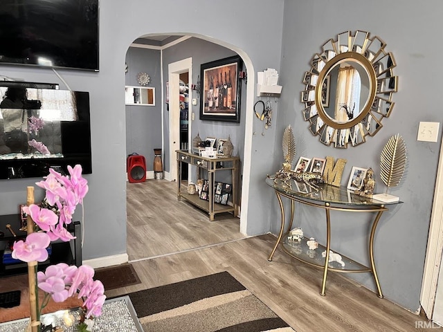 corridor with baseboards, arched walkways, and wood finished floors