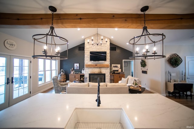 kitchen with a chandelier, vaulted ceiling with beams, a fireplace, and open floor plan