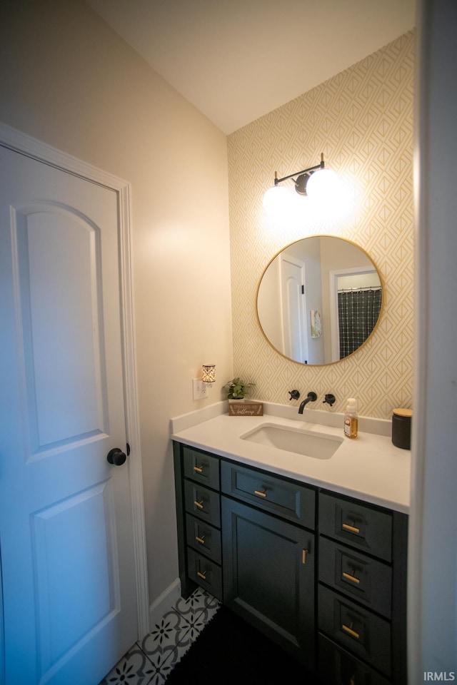 bathroom featuring baseboards, vanity, and wallpapered walls