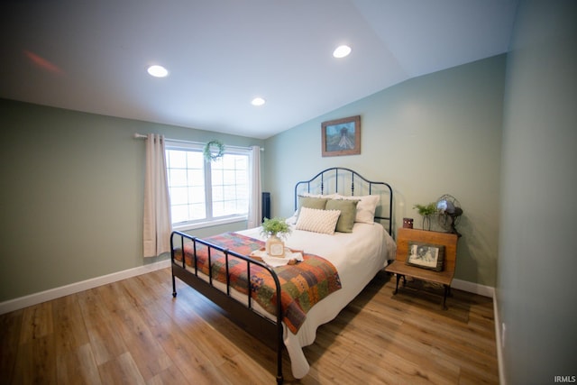 bedroom featuring lofted ceiling, light wood finished floors, and baseboards