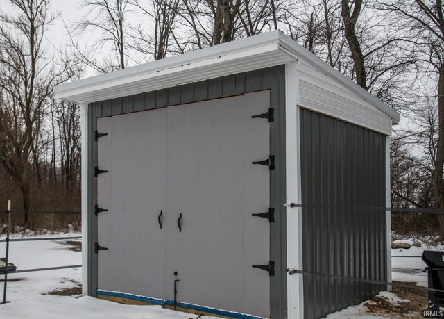 snow covered structure with an outbuilding and a storage unit