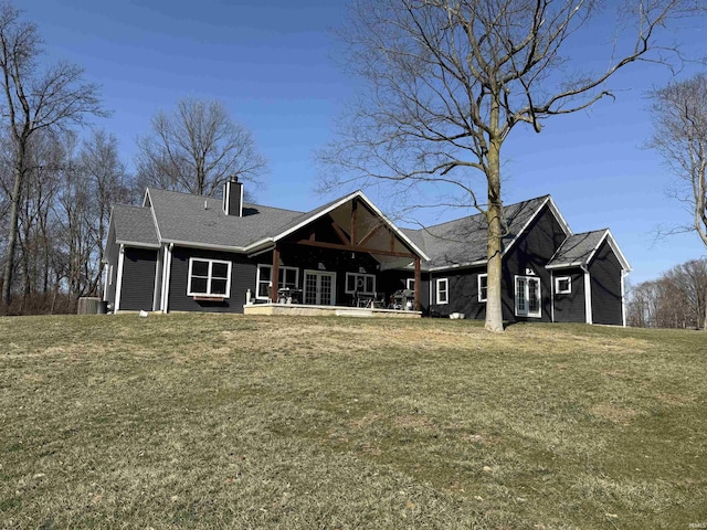 rear view of house with french doors, a chimney, and a lawn