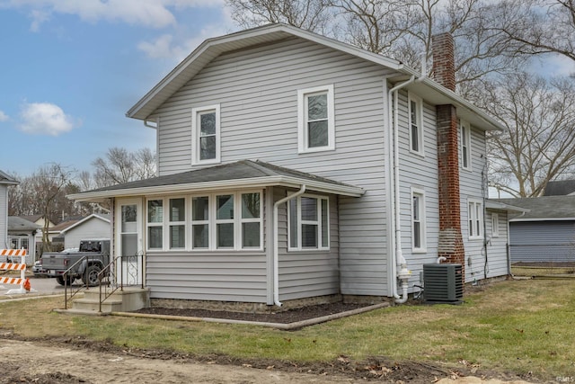 exterior space with cooling unit, a chimney, and a front yard