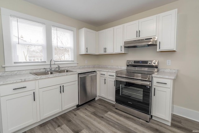 kitchen featuring light countertops, appliances with stainless steel finishes, white cabinets, a sink, and under cabinet range hood