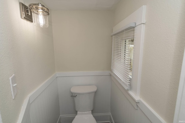 bathroom with a wainscoted wall and toilet