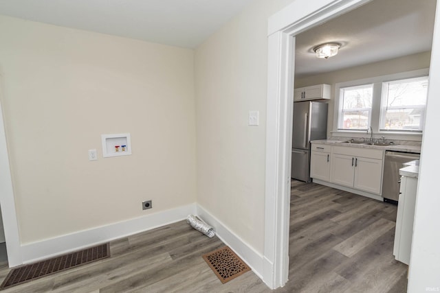 clothes washing area featuring washer hookup, hookup for an electric dryer, a sink, and wood finished floors