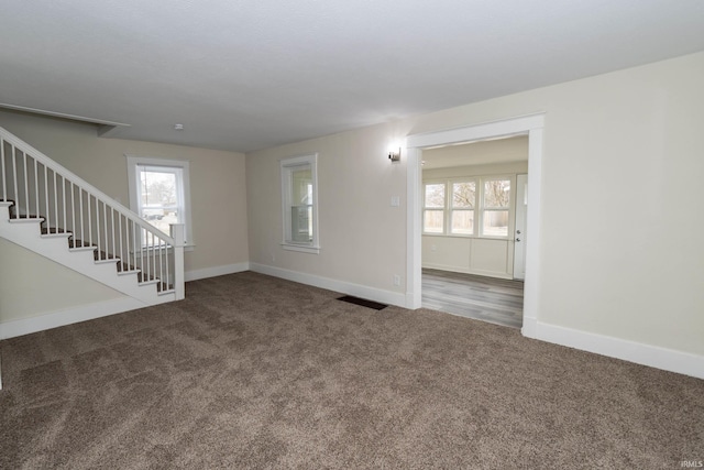 spare room with a healthy amount of sunlight, stairs, visible vents, and carpet flooring