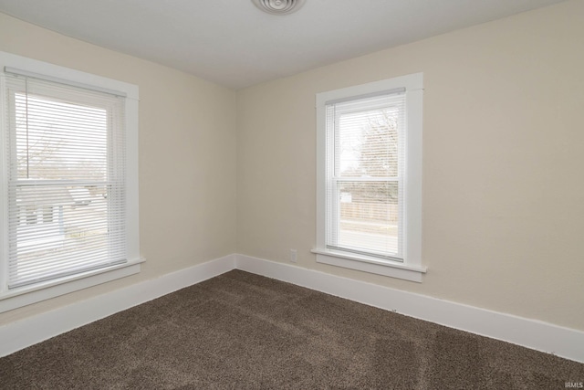 spare room with dark carpet and baseboards