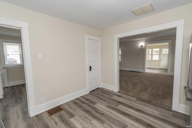 spare room featuring baseboards, visible vents, and wood finished floors