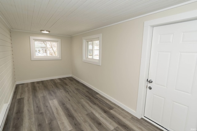 empty room with wood ceiling, crown molding, baseboards, and wood finished floors