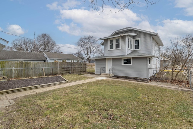 back of house featuring a garden, fence, and a lawn