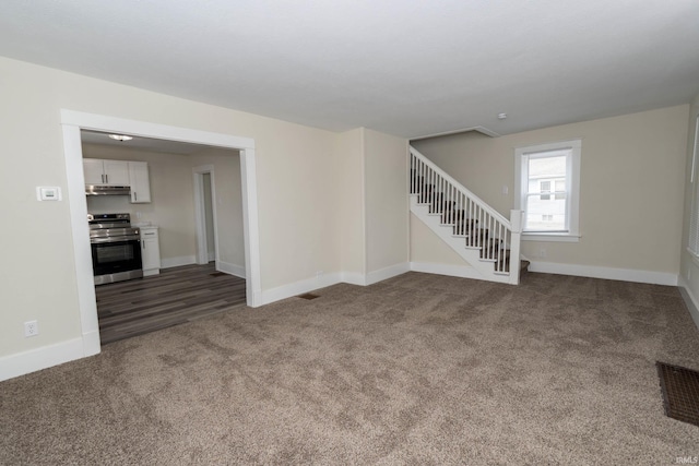 carpeted spare room featuring stairway, visible vents, and baseboards