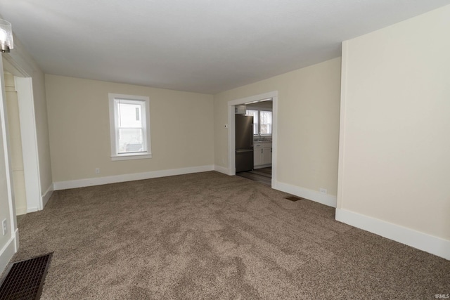 carpeted spare room featuring visible vents and baseboards