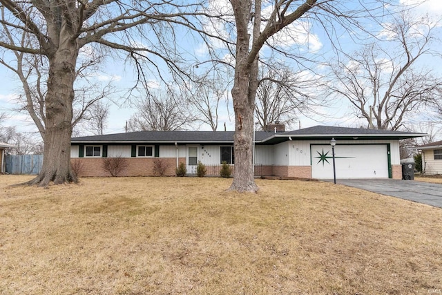 ranch-style home with an attached garage, brick siding, driveway, a chimney, and a front yard