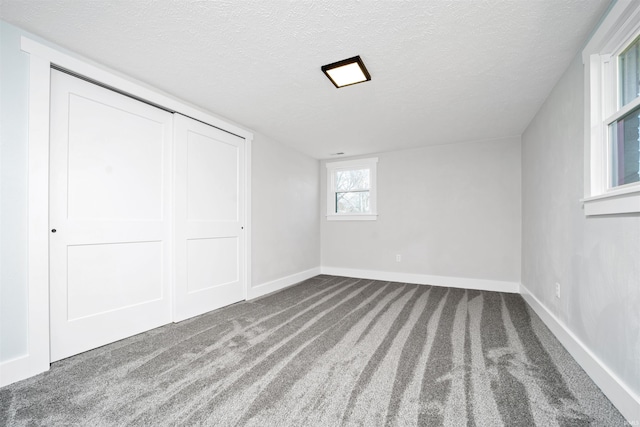 unfurnished bedroom featuring carpet floors, a closet, baseboards, and a textured ceiling