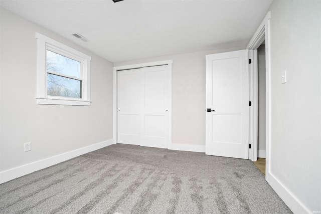 unfurnished bedroom with carpet floors, a closet, visible vents, and baseboards