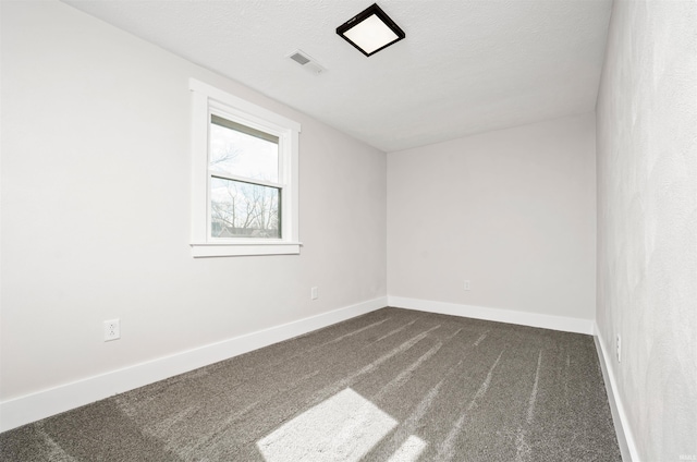 spare room with dark colored carpet, visible vents, a textured ceiling, and baseboards