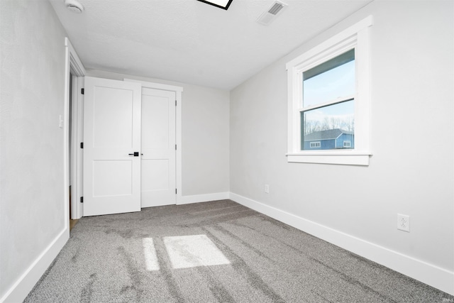 unfurnished bedroom with carpet flooring, visible vents, baseboards, and a textured ceiling