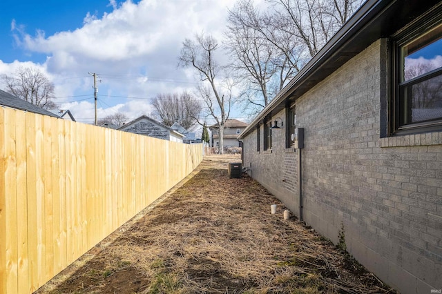 exterior space with brick siding, cooling unit, and fence