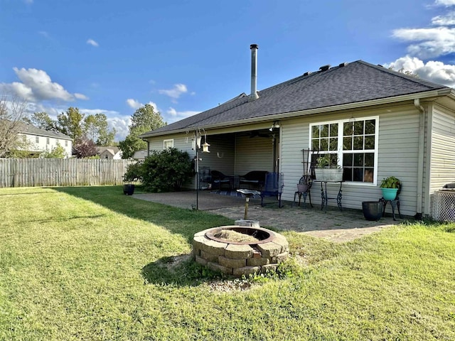 back of house featuring a shingled roof, a lawn, a patio area, fence, and a fire pit