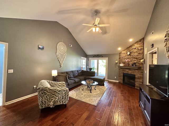 living room featuring a ceiling fan, baseboards, dark wood-style flooring, and a stone fireplace