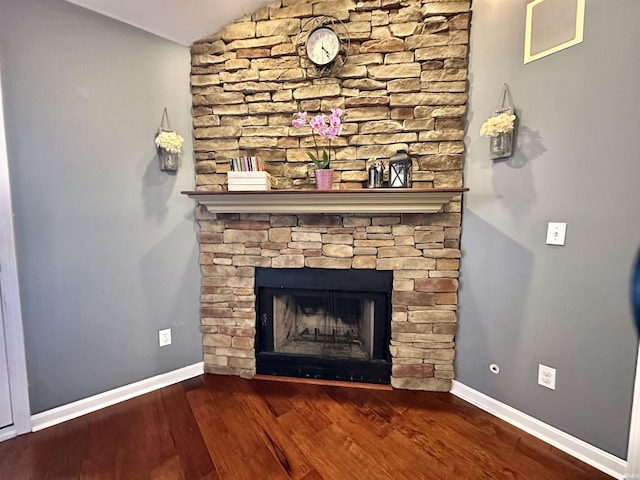 interior details featuring baseboards, wood finished floors, and a stone fireplace