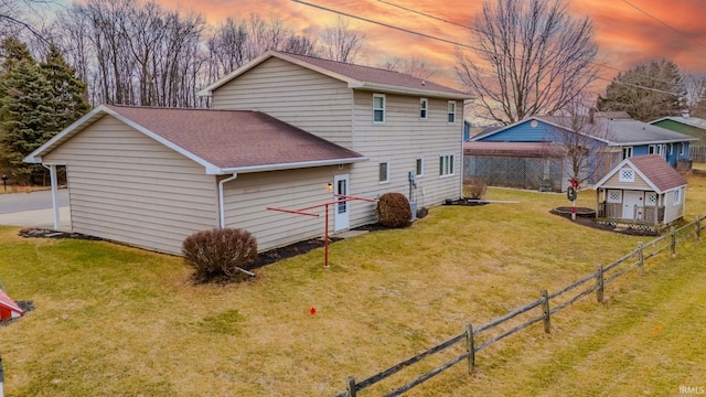 back of property with roof with shingles, a yard, and fence