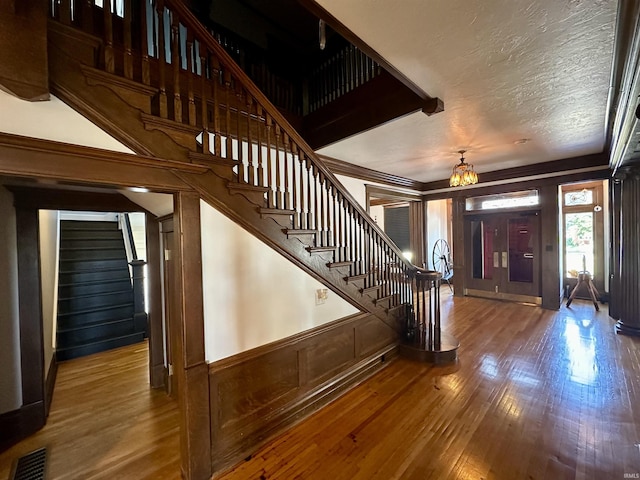 foyer featuring wood finished floors, visible vents, a wainscoted wall, and stairs