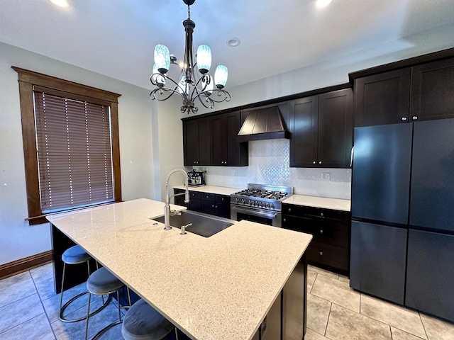 kitchen with stainless steel stove, a sink, custom range hood, freestanding refrigerator, and pendant lighting