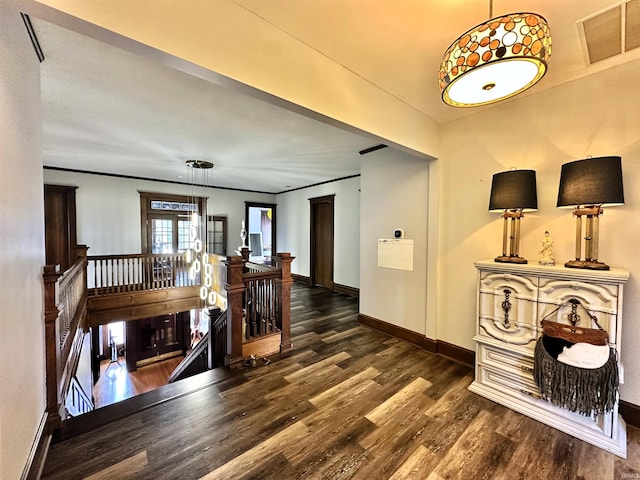 hall with baseboards, visible vents, dark wood finished floors, and an upstairs landing