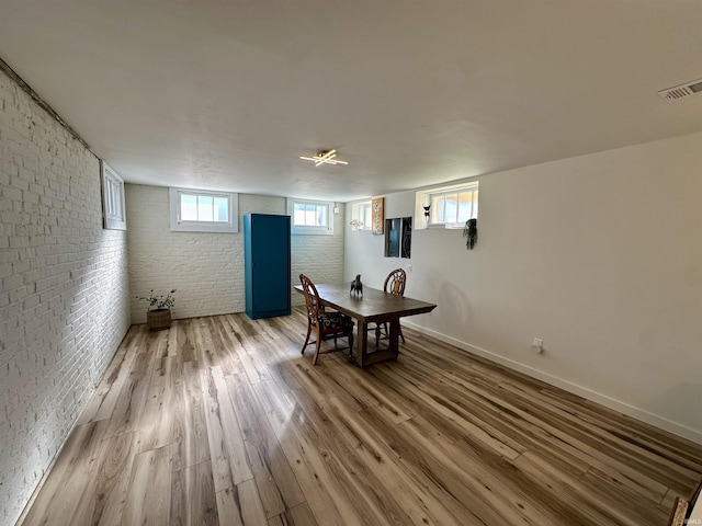 dining space with brick wall, wood finished floors, visible vents, and baseboards