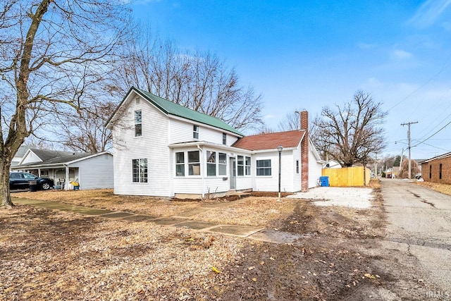 exterior space with a sunroom, a chimney, and aphalt driveway