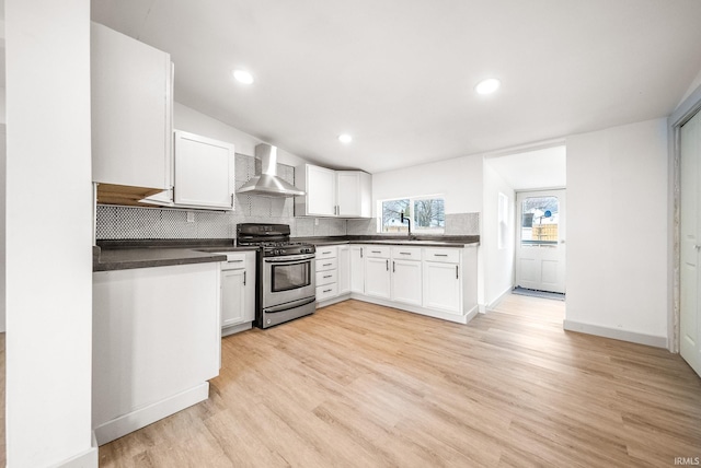 kitchen featuring dark countertops, wall chimney exhaust hood, stainless steel range with gas cooktop, and decorative backsplash