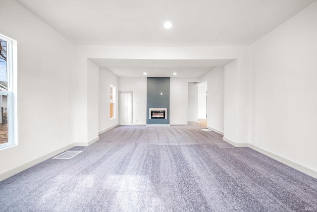 unfurnished living room with carpet floors, recessed lighting, visible vents, a large fireplace, and baseboards