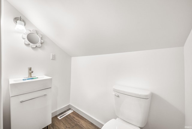 bathroom with toilet, wood finished floors, visible vents, baseboards, and vaulted ceiling