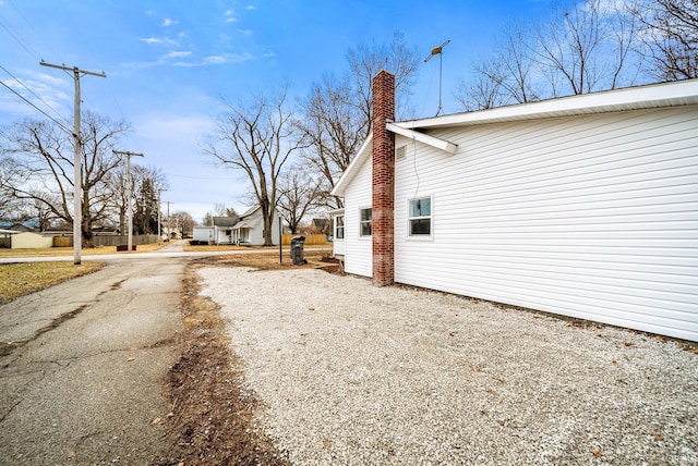 view of home's exterior featuring driveway and a chimney