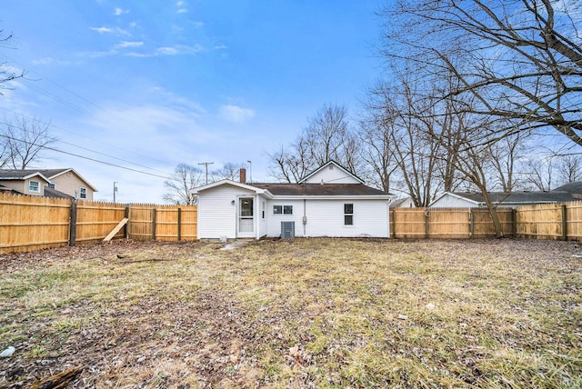 rear view of house with a fenced backyard and a chimney