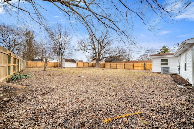 view of yard with cooling unit, a fenced backyard, an outdoor structure, and a shed