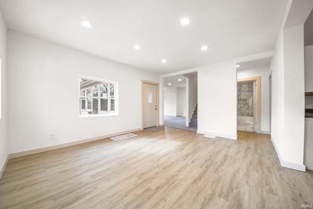 unfurnished living room with light wood finished floors, baseboards, stairway, and recessed lighting