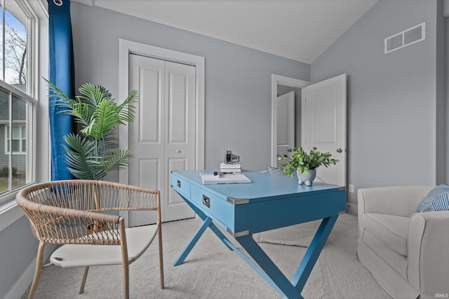 office featuring light colored carpet, visible vents, lofted ceiling, and baseboards