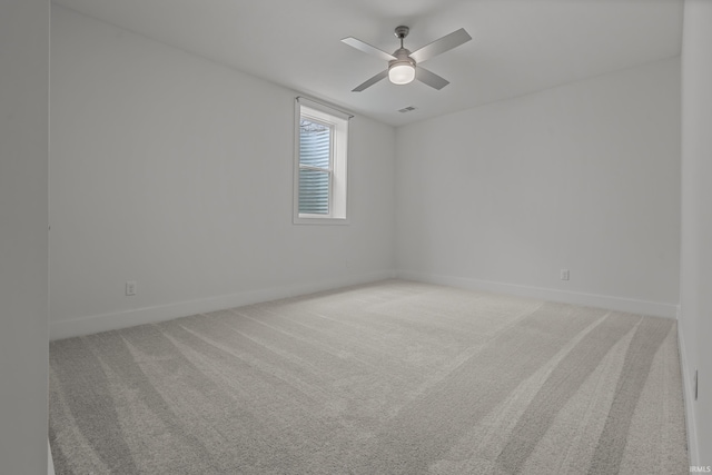 spare room featuring ceiling fan, baseboards, and light colored carpet