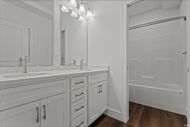 full bath with double vanity, bathtub / shower combination, a sink, and wood finished floors