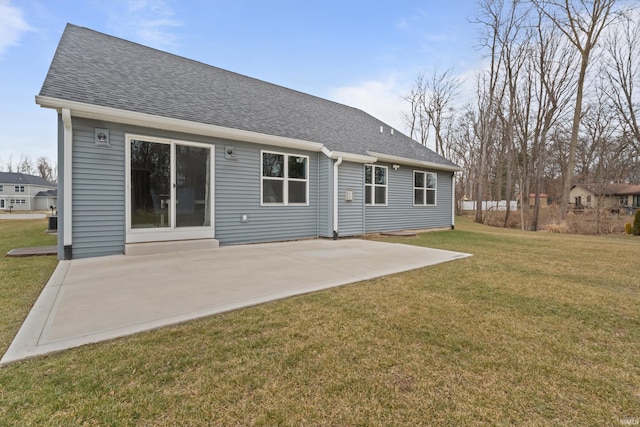 back of house with a yard, roof with shingles, and a patio